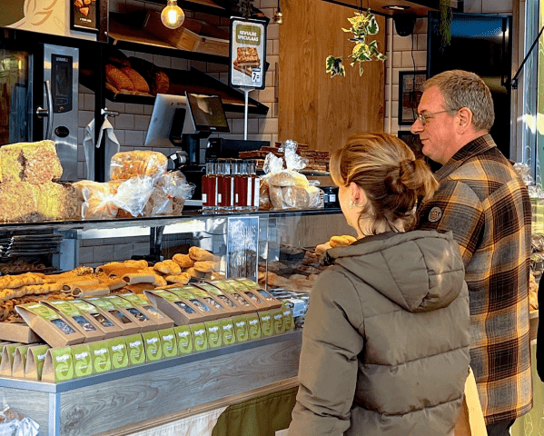 Klanten bij de toonbank van Bakkerij Hartjes met gevulde speculaas en vers banket in de vitrine.