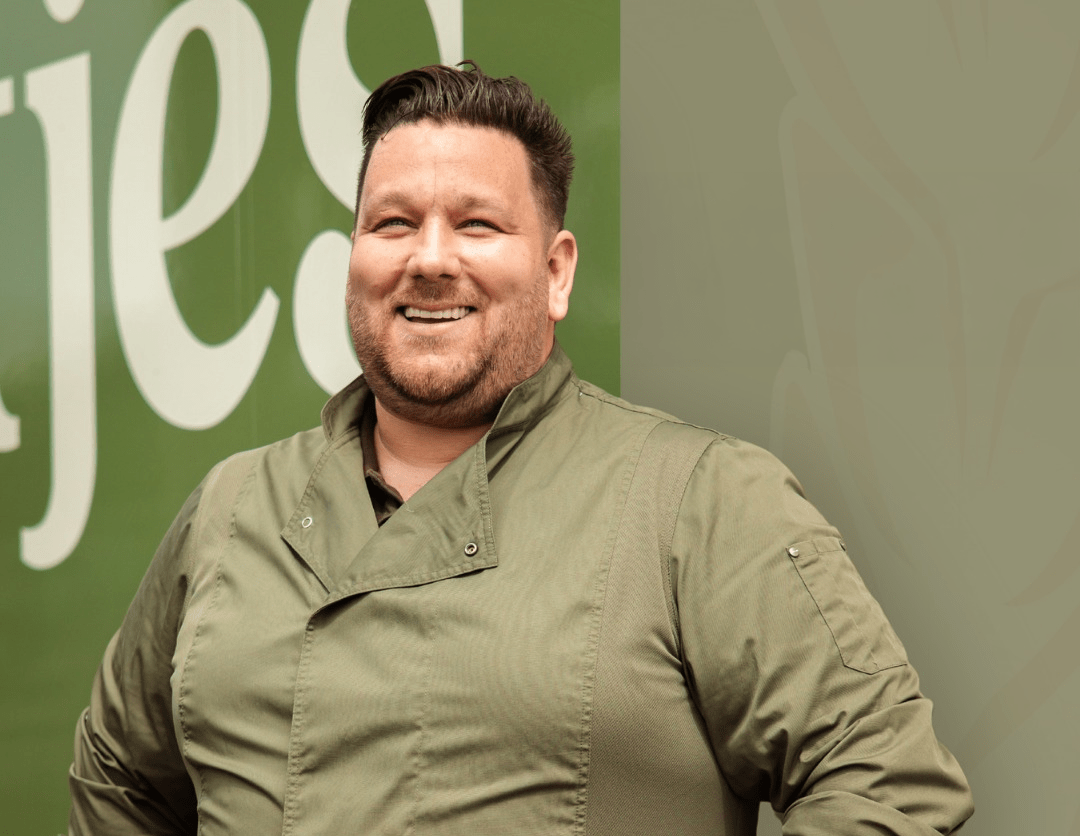 Elmar Hartjes, eigenaar van bakkerij Hartjes brood & banket, lachend poserend in zijn bakkersjas.